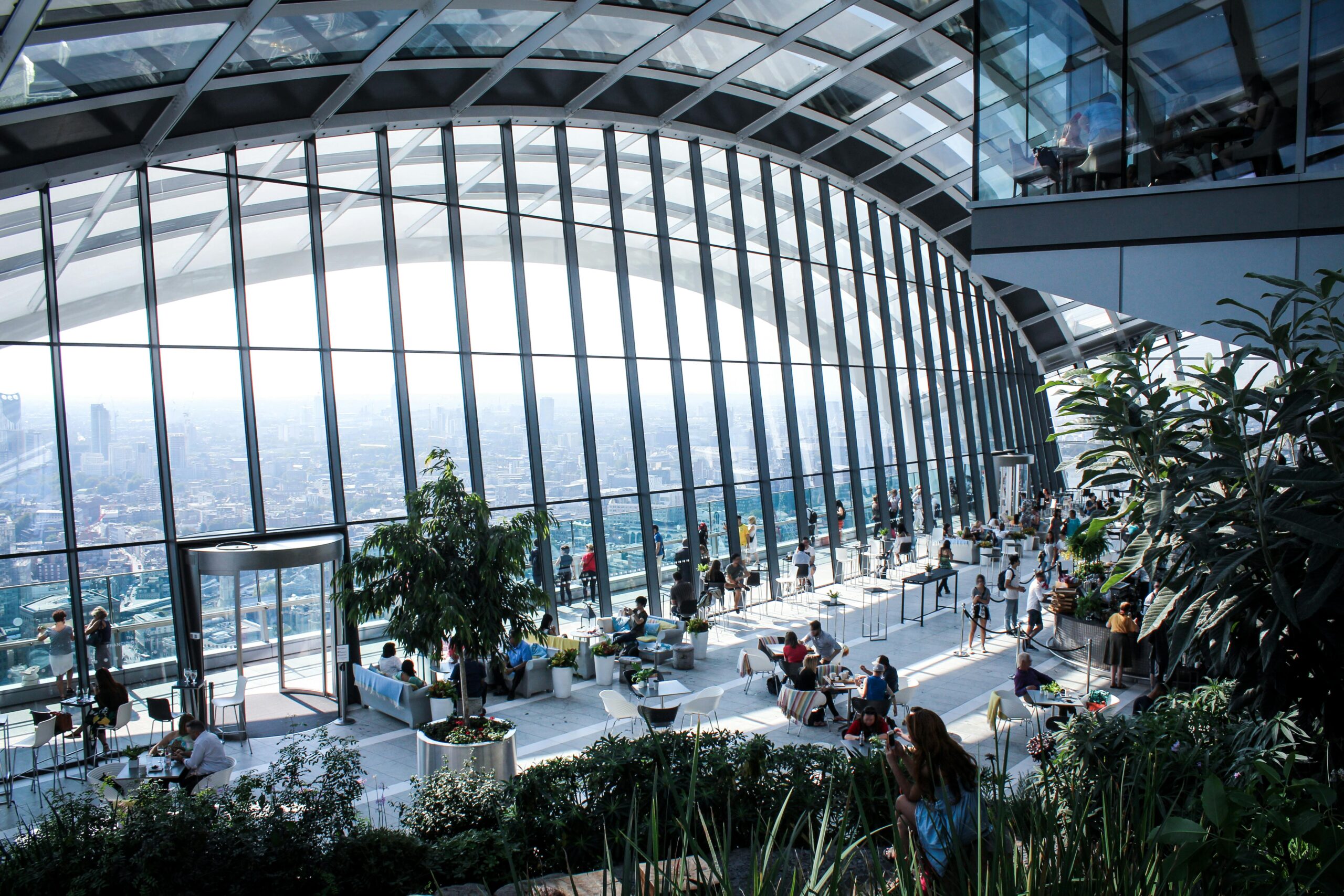 A spacious and modern atrium featuring lush greenery and a stunning panoramic city view.